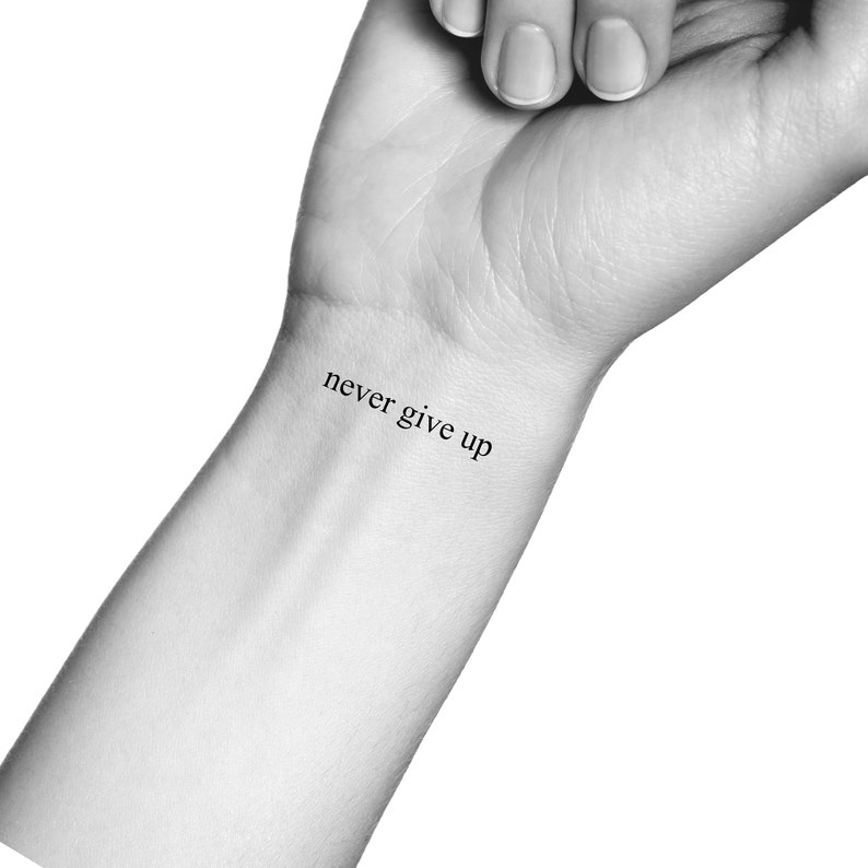 Może przedstawiać: Czarno-białe zdjęcie nadgarstka z tatuażem "never give up".