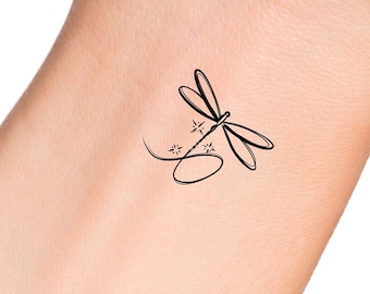 May include: A simple black line drawing of a dragonfly with a few stars on its wings. The dragonfly is on a light skin tone background.