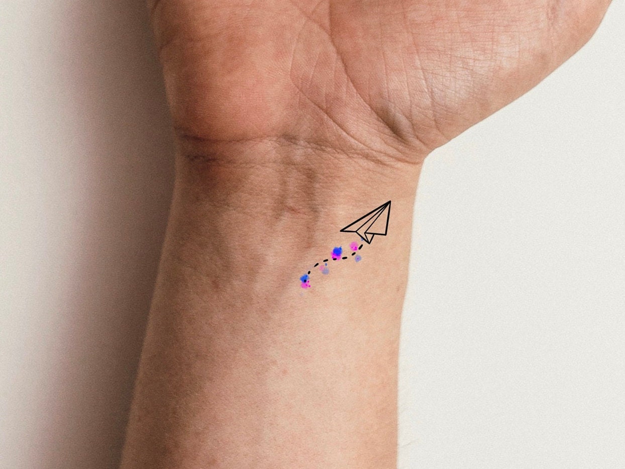 Paper plane tattoo on the inner forearm.