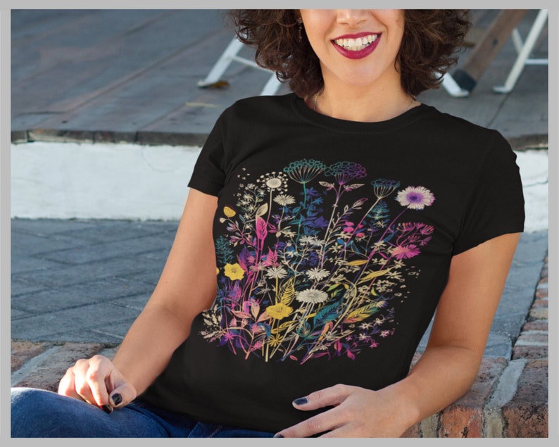 Peut inclure: Un t-shirt noir avec un imprim&eacute; floral color&eacute;. Les fleurs sont dans des tons de rose, violet, jaune et bleu. L'impression est un motif stylis&eacute; d'un bouquet de fleurs sauvages.