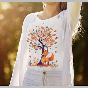 May include: White t-shirt with a vibrant illustration of a tree with autumn leaves and a fox. The design features orange, yellow, and green leaves, with the fox positioned under the tree. The shirt is paired with white trousers and a white jacket.