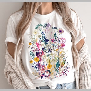 Peut inclure: T-shirt blanc avec un imprim&eacute; floral color&eacute; compos&eacute; de diff&eacute;rentes fleurs et feuilles dans des tons de rose, violet, jaune, vert et bleu.