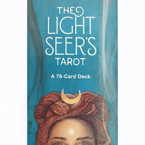 May include: A tarot deck titled "The Light Seer's Tarot" with a teal background. The cover features a woman's face with red hair, a crescent moon, and the text "A 78-Card Deck".