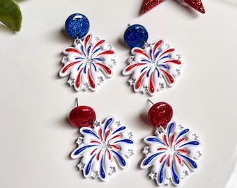 Puede incluir: Cuatro pares de pendientes de temática patriótica. Cada pendiente presenta un diseño de estrella blanca con detalles en rojo y azul. Los pendientes tienen cierre de poste y están rematados con una bola brillante roja o azul.