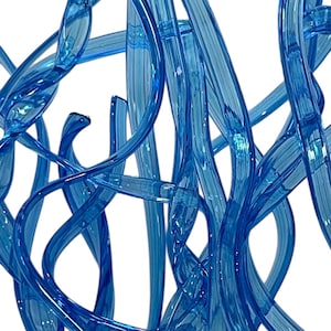 May include: A collection of translucent blue glass rods arranged in a vertical, intertwined, and curved formation. The glass elements feature a smooth, glossy surface with varying thicknesses and lengths, creating a complex, multi-layered structure.