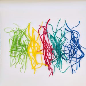 May include: An abstract composition featuring colorful, wavy lines in green, yellow, red, teal, and blue. The lines are arranged in a semi-organized manner against a white background, creating a vibrant and playful visual.