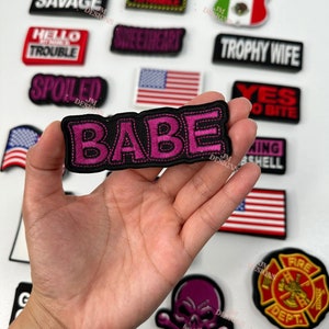 Könnte beinhalten: Eine Sammlung von gestickten Bügelbildern mit verschiedenen Sprüchen und Designs, darunter "High Maintenance", "Savage", "Hello My Name Is Trouble", "Spoiled", "Babe", "Milf", "Sweetheart", "Mexico", "Trophy Wife", "Yes To Bite", "Warning Shell", "Fire Dept." und ein Totenkopf mit Knochen.
