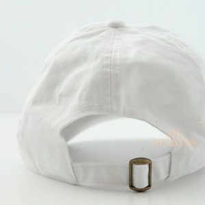May include: A white baseball cap with an adjustable strap in the back. The cap is made of a soft, cotton fabric.