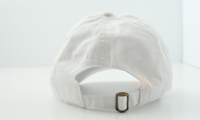 May include: A white baseball cap with an adjustable strap in the back. The cap is made of a soft, cotton fabric.