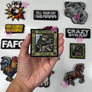May include: A collection of embroidered patches with various designs. One patch features a mountain landscape with the text "PICCHU INCA TRAIL". Other patches include a dog, a rooster, a horse, and text like "GIVE RESPECT GET RESPECT".