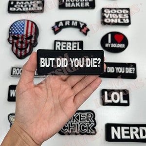 May include: A collection of black and white iron-on patches with various phrases and designs, including "#NOFILTER", "NO THANKS", "I MAKE CUTE BABIES", "TROUBLE MAKER", "ARMY", "REBEL", "BUT DID YOU DIE?", "GOOD VIBES ONLY", "MY SOLDIER", "DID YOU DIE?", "LOL", "BIKER CHICK", "NERD", "ANUT", and "BIKER BABE".
