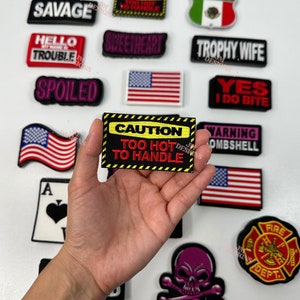 Könnte beinhalten: Eine Sammlung von gestickten Bügelbildern mit verschiedenen Sprüchen und Designs, darunter "High Maintenance", "Savage", "Hello My Name Is Trouble", "Spoiled", "MILF", "Mexico", "Sweetheart", "Trophy Wife", "Yes I Do Bite", "Warning Bombshell", "Caution Too Hot To Handle", "Fire Dept." und ein Totenkopf mit Knochen.