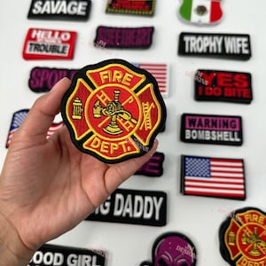 May include: A collection of embroidered iron-on patches with various phrases and designs. The patches include "High Maintenance", "Savage", "Hello Trouble", "Sweetheart", "Fire Dept", "MILF", "Mexico", "Trophy Wife", "Yes I Do Bite", "Warning Bombshell", "Good Girl Gone Bad", "King Daddy", and a skull and crossbones design.