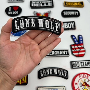 May include: A collection of iron-on patches with various designs, including "Lone Wolf", "Old Skool", "Southern Belle", "Security", "Bad Example", "Fire Department", and "Route 66".