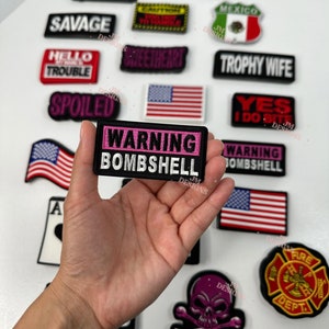 May include: A collection of embroidered iron-on patches with various designs and phrases, including "Warning Bombshell", "Trophy Wife", "Yes I Do", "Sweetheart", "Savage", "High Maintenance", "Hello Trouble", "Spoiled", "Milf", "Mexico", and "Fire Dept.".