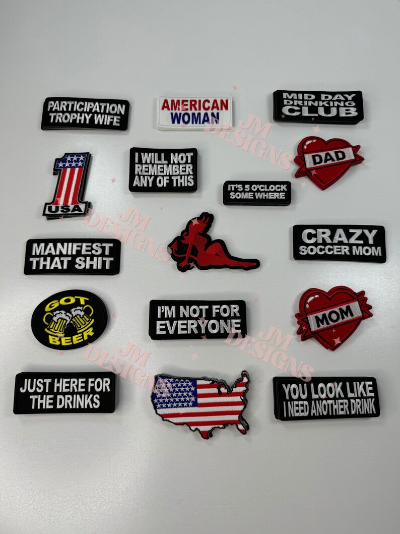 May include: A collection of 14 iron-on patches with various designs and sayings. The patches are mostly white, black, red, and blue. Some of the sayings include "Participation Trophy Wife", "American Woman", "I Will Not Remember Any Of This", "Manifest That Shit", "Got Beer", "I'm Not For Everyone", "Just Here For The Drinks", "Mid Day Drinking Club", "Dad", "It's 5 O'Clock Somewhere", "Crazy Soccer Mom", "Mom", and "You Look Like I Need Another Drink".