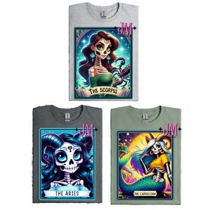 May include: Three t-shirts with different zodiac signs. Each shirt features a colorful illustration of a skeleton woman with a different zodiac sign. The first shirt features a woman with a scorpion, the second shirt features a woman with a ram, and the third shirt features a woman with a goat.