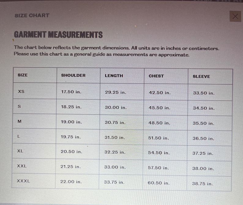 Puede incluir: Una tabla de tallas de prendas con medidas en pulgadas. La tabla muestra las medidas de hombro, largo, pecho y manga para las tallas XS a XXXL. Las medidas son aproximadas.