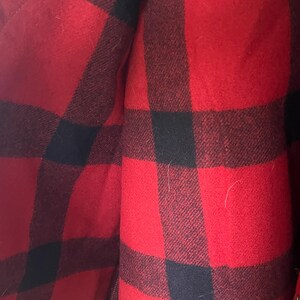 Puede incluir: Primer plano de un patr&oacute;n de cuadros rojos y negros. La tela parece ser un material grueso y tejido, posiblemente lana o una mezcla de lana. El patr&oacute;n es un cl&aacute;sico estampado de cuadros de b&uacute;falo, con cuadrados grandes y audaces de rojo y negro.