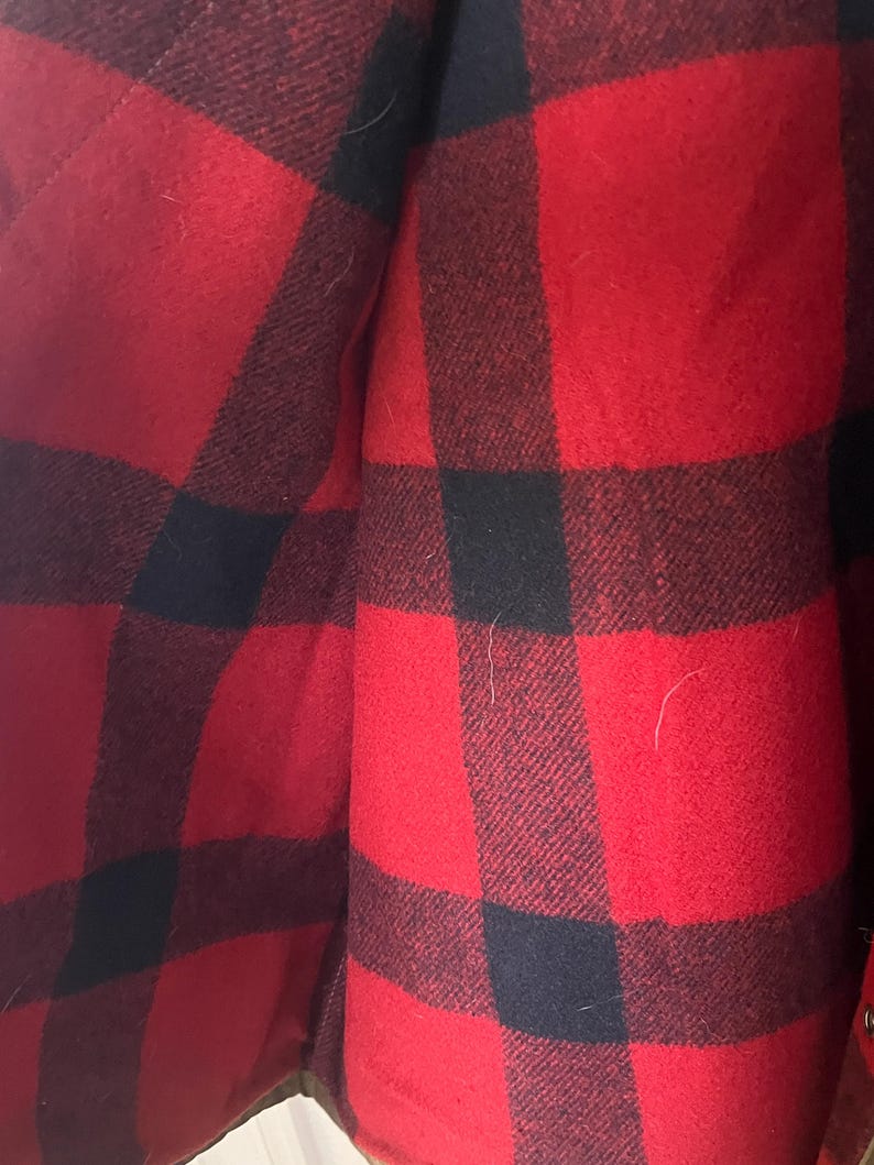 Puede incluir: Primer plano de un patr&oacute;n de cuadros rojos y negros. La tela parece ser un material grueso y tejido, posiblemente lana o una mezcla de lana. El patr&oacute;n es un cl&aacute;sico estampado de cuadros de b&uacute;falo, con cuadrados grandes y audaces de rojo y negro.