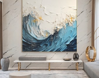 May include: Abstract painting of a blue wave crashing against a white background with gold accents. The painting is framed in a gold frame and is hanging on a white marble wall.
