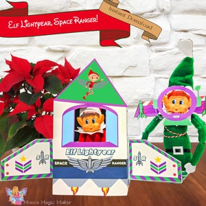Op de afbeelding: Een printbaar knutselwerk voor kinderen met een elf verkleed als Buzz Lightyear uit de Toy Story-film. De elf staat in een raket met de woorden "Elf Lightyear, Space Ranger!" en "Elf Lightyear" op de voorkant. De printbare bevat een raket, vleugels en een helm voor de elf.
