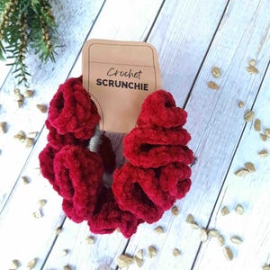 May include: A red crocheted scrunchie with a brown paper tag that says "Crochet Scrunchie".