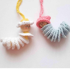 May include: Two handmade crochet caterpillar ornaments. One has a yellow and white daisy-like design, and the other has a pink hat and blue body. Each has a wooden head with a painted cat face and a yarn loop for hanging.
