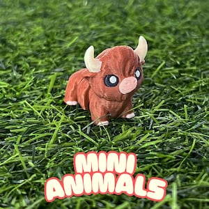 May include: A small, brown, 3D printed bull figurine with white horns and black eyes. The figurine is sitting on a bed of green grass. The text "MINI ANIMALS" is printed in pink letters on the grass.