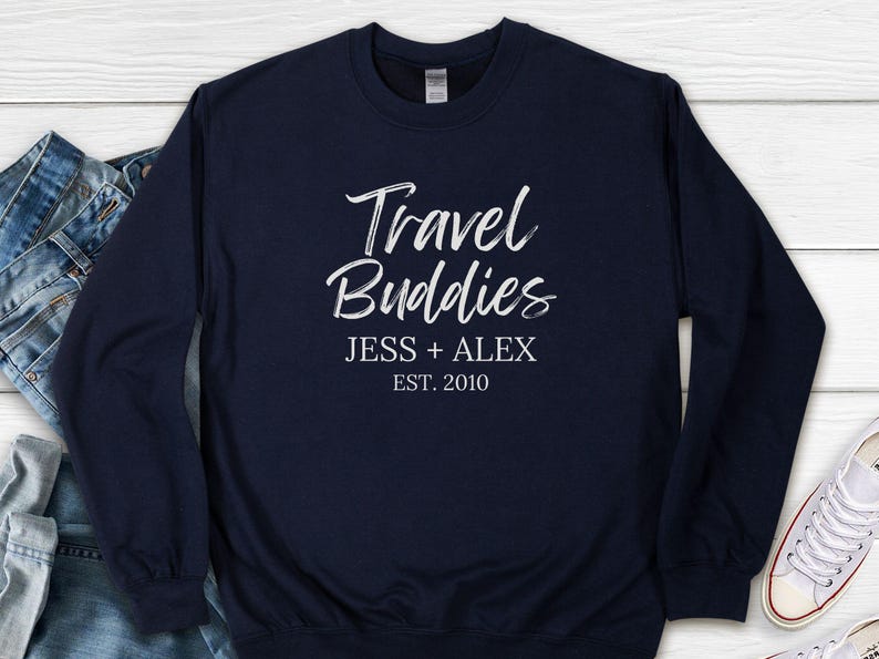 May include: Navy blue long-sleeved sweatshirt with white text that reads "Travel Buddies Jess + Alex Est. 2010".