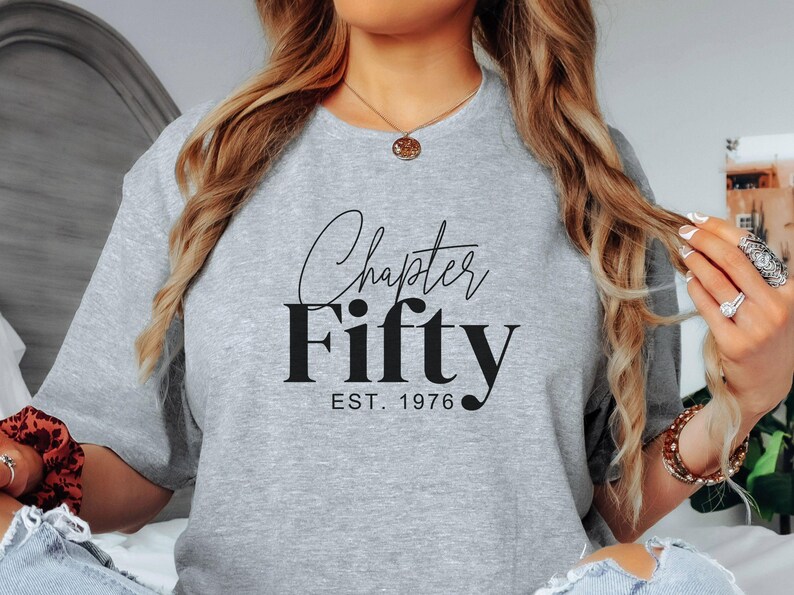 May include: A light gray sweatshirt with the words "Chapter Fifty" in a black script font, with "EST. 1976" below. The sweatshirt is a crew neck style.