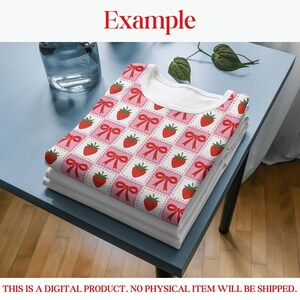 Op de afbeelding: Een stapel witte t-shirts met een aardbeien- en strikpatroon. Het ontwerp toont rode aardbeien en strikken op een roze en witte geruite achtergrond. Het woord "Example" staat bovenaan de afbeelding.