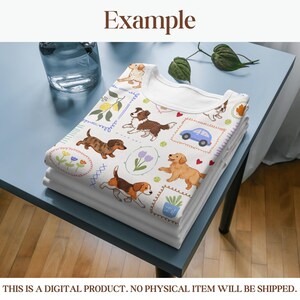 K&ouml;nnte beinhalten: Ein Stapel gefalteter wei&szlig;er T-Shirts mit einem farbenfrohen Muster zum Thema Hunde. Das Muster zeigt verschiedene Hunderassen, Blumen und ein blaues Auto. Der Text "Example" befindet sich oben im Bild.