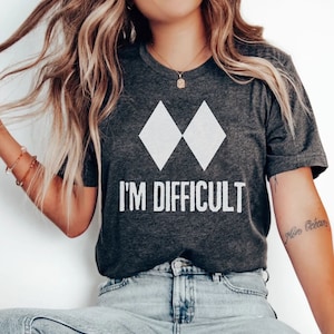 May include: A dark gray t-shirt with a white graphic of two diamonds and the text "I'm Difficult".