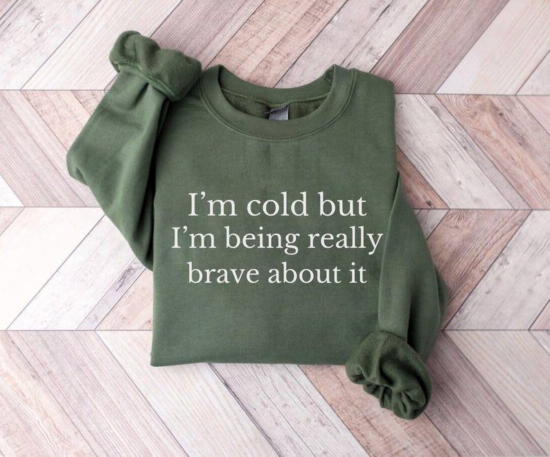 May include: A green sweatshirt with the text "I'm cold but I'm being really brave about it" printed in white.