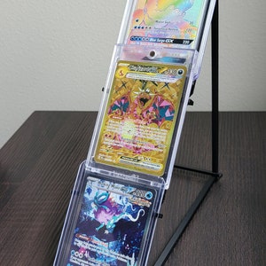 May include: Three Pokemon trading cards graded by CGC in a black card stand. The cards are "Wishiwashi GX" graded a 10, "Gyarados GX" graded a 9, and "Walking Wake" graded a 9.