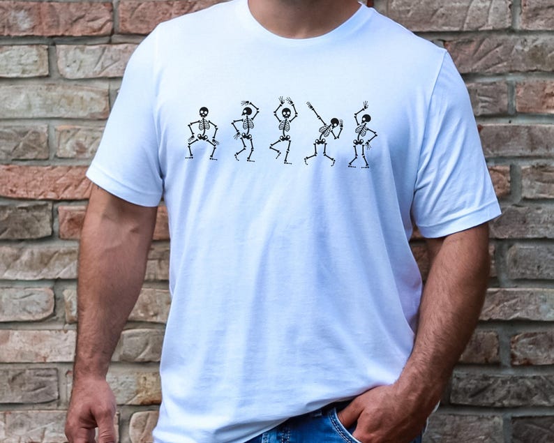 May include: White t-shirt with a graphic of five skeletons dancing. The skeletons are black and white and are in different poses.