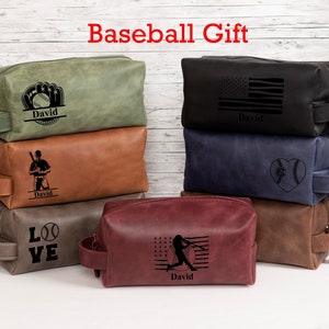 May include: Six different personalized leather toiletry bags with baseball-themed designs. The bags are stacked in a pyramid shape and feature various designs, including a baseball glove, a baseball player, a baseball heart, and a baseball bat. The bags are all personalized with the name "David".