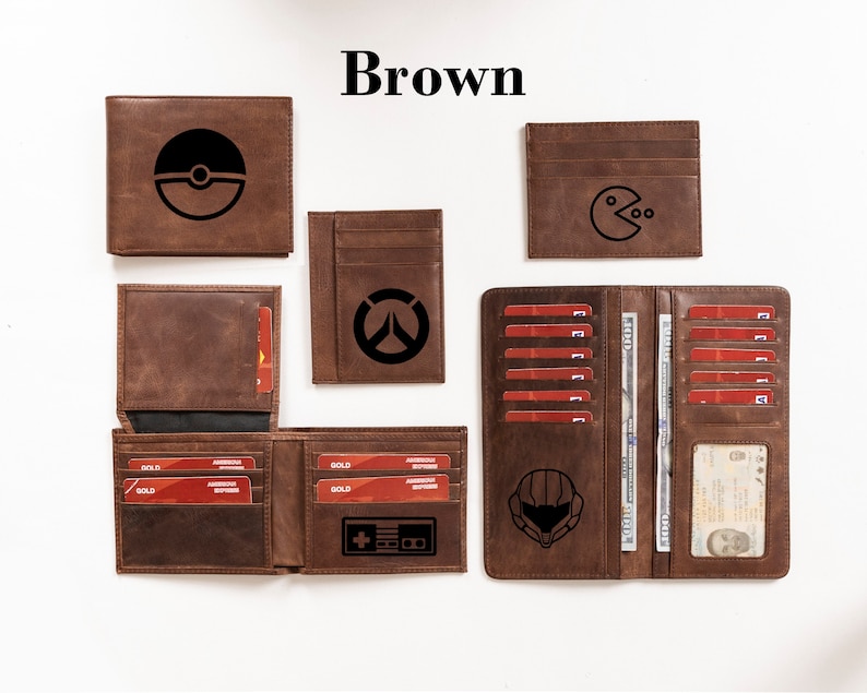 May include: A set of brown leather wallets with various designs, including a Pokeball, Pac-Man, Overwatch logo, and a Halo helmet. The wallets have multiple card slots and a money clip.