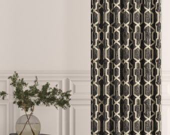 May include: A floor-length curtain featuring a dark charcoal grey fabric with a repeating cream-coloured geometric lattice pattern. The curtain hangs vertically, displaying a structured, symmetrical design of interconnected hexagonal shapes.