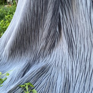 May include: A light grey fabric with a vertical crinkled texture and a subtle sheen. The text "color pattern number:2" is printed vertically on the left side of the material, which features deep, narrow folds throughout the surface.