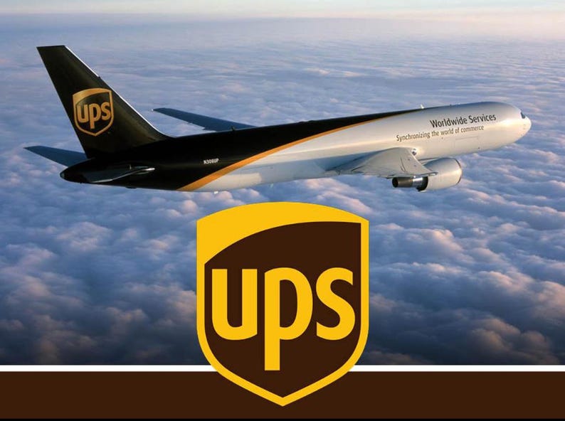 May include: A UPS cargo aeroplane flying above clouds with a black tail featuring the brown and gold UPS shield logo. The white fuselage displays the text Worldwide Services Synchronizing the world of commerce and a large UPS shield logo.