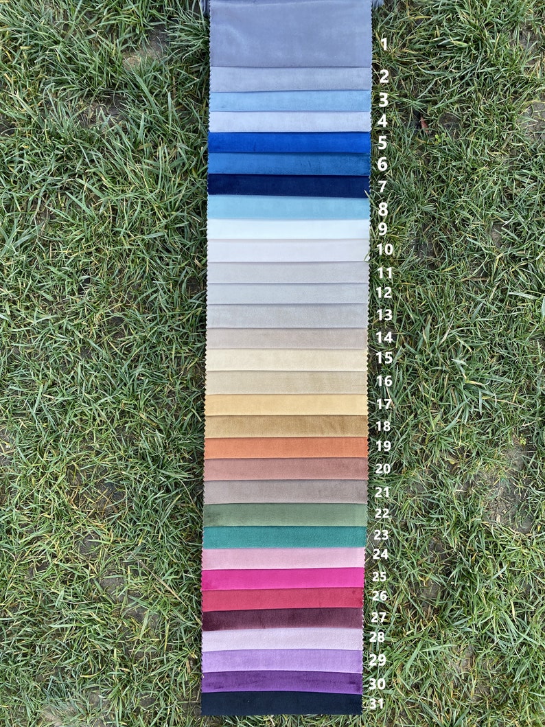 May include: A vertical fabric swatch sample strip featuring thirty-one distinct colour variations of velvet material, arranged in a gradient from light grey to dark blue, beige, earth tones, pinks, greens, and deep purple.
