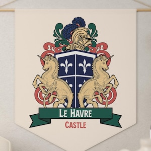Könnte beinhalten: Ein cremefarbenes Wandbehang mit einem heraldischen Design. Das Wappen zeigt zwei goldene Einhörner, die einen Schild mit Lilien-Symbolen flankieren. Der Text "LE HAVRE CASTLE" ist auf einem grünen Banner zu sehen.