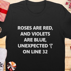 Könnte beinhalten: Schwarzes T-Shirt mit weißem Text, der "Roses are red, and violets are blue, unexpected '{' on line 32" lautet.