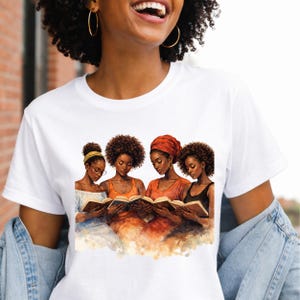 Puede incluir: Camiseta blanca con una ilustraci&oacute;n en acuarela de cuatro mujeres negras leyendo libros. Las mujeres tienen diferentes peinados y cubrecabezas, usando tops de varios colores. La obra de arte tiene tonos c&aacute;lidos y un estilo suave y pict&oacute;rico.