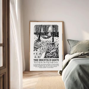 May include: A framed black and white poster with a detailed illustration of a bird, palm trees, and a hammock. The text "THE MOUNTAIN GOATS" is displayed, along with tour dates. The artwork has a vintage aesthetic, suitable for a music fan.