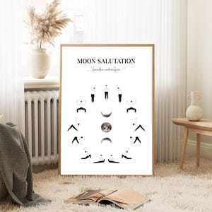 May include: A framed print featuring a yoga sequence, with the title "Moon Salutation" in black text. The print displays a series of poses around a central image of the moon phases. The artwork is set against a white background.