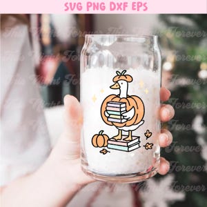 May include: A clear glass can-shaped cup with a cartoon goose wearing a pumpkin costume and holding books. The design includes a small pumpkin, leaves, and the text "SVG PNG DXF EPS".