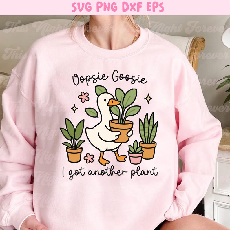 以下が含まれることがあります： 「Oopsie Goosie I got another plant」の文字と、植木鉢を持ったガチョウのグラフィックが描かれた、薄いピンク色のスウェットシャツ。デザインには、いくつかの鉢植えと装飾的な要素が含まれています。